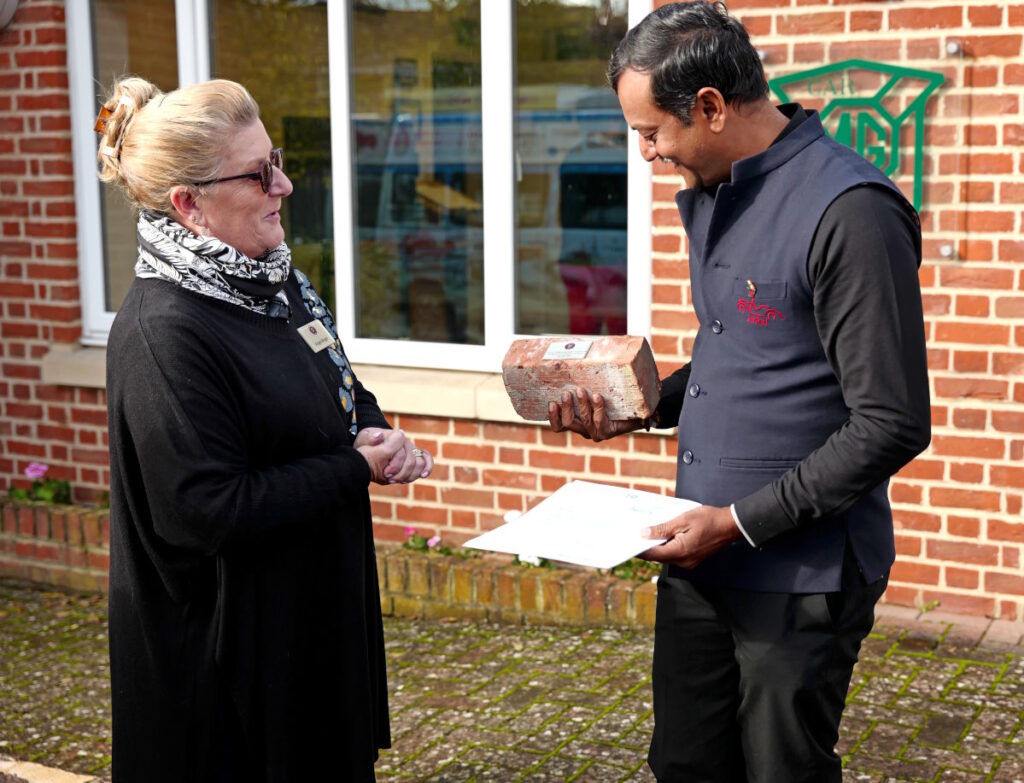 Angie Wright MG Car Club Abingdon Work Centre Chair presenting Daman Thakore with a brick from the Abingdon MG factory